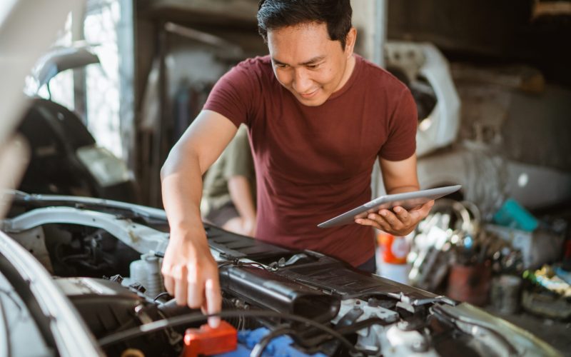 young-male-mechanic-wiring-battery-while-using-digital-tablet-repair-shop (1)